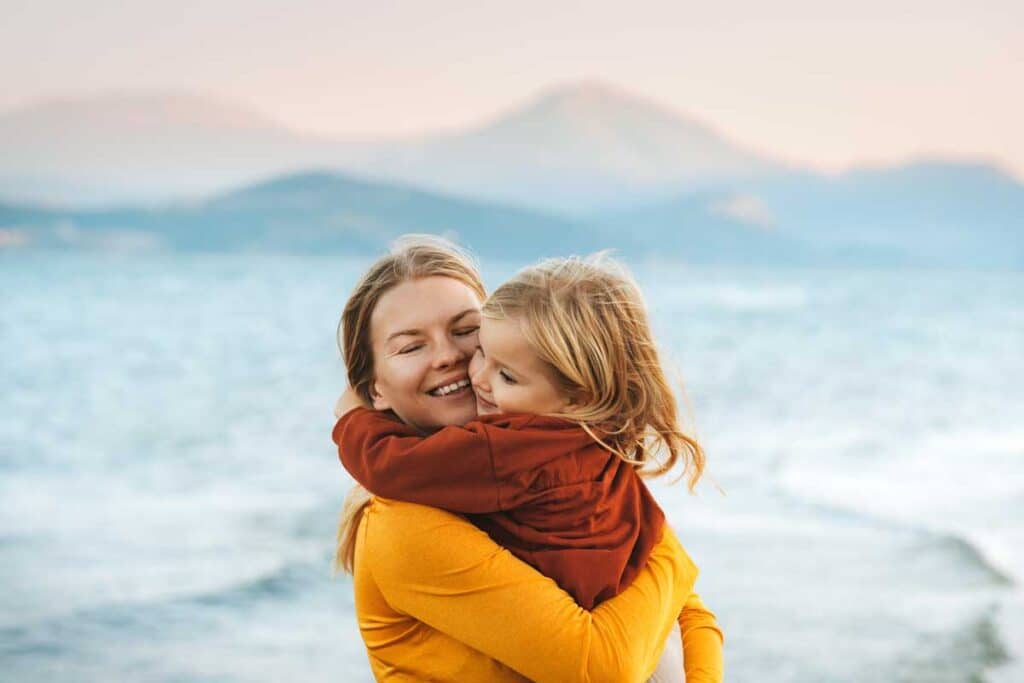 Mother hugging with child daughter family lifestyle happy emotions travel together summer vacations woman with kid walking outdoor at the lake Mothers day holiday